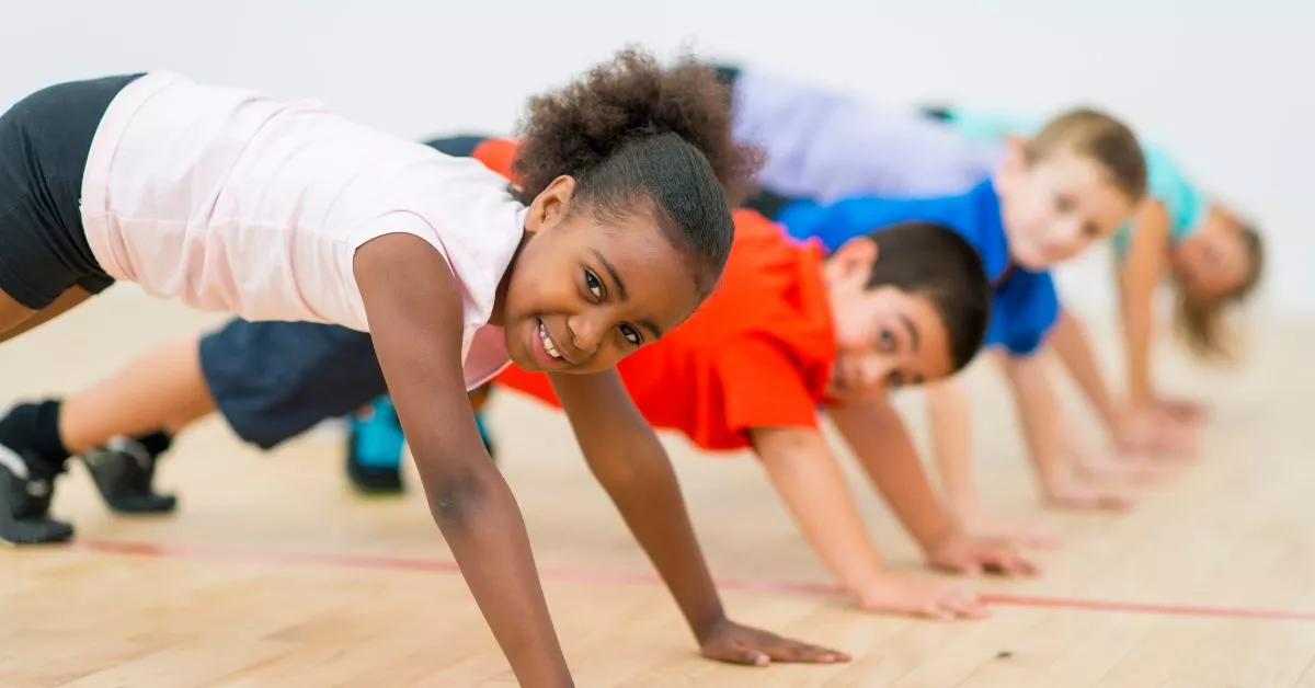 A group of children doing bear-crawl exercises on a gym floor, showcasing the fun and active environment of ninja warrior training for kids.