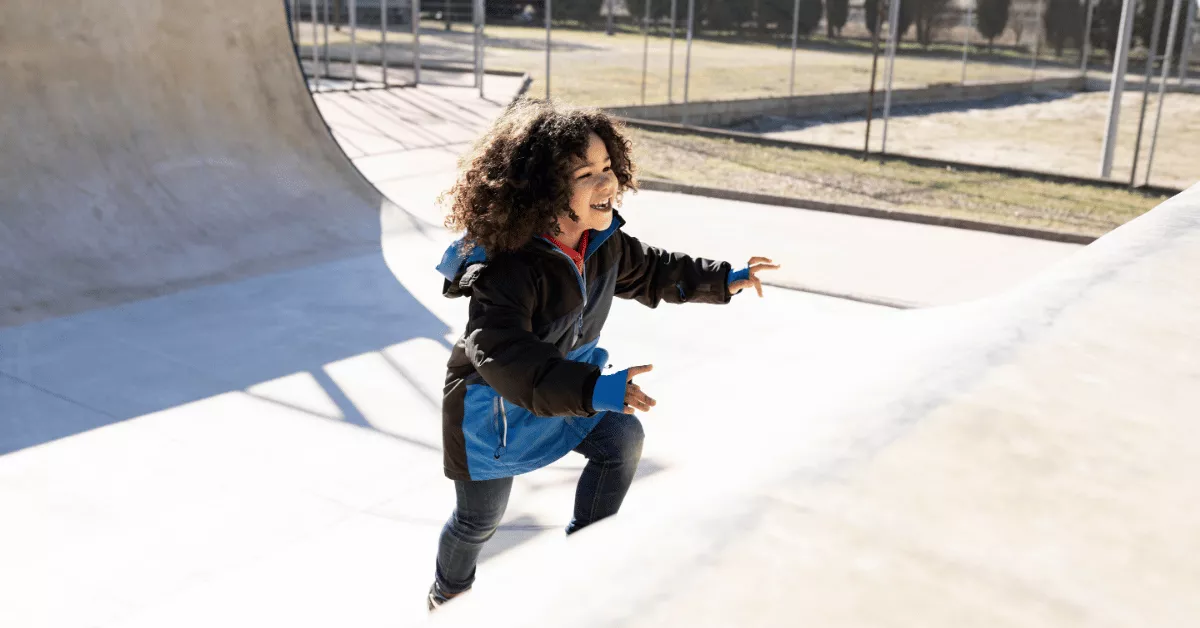 Child running up an outdoor obstacle ramp, representing the dynamic movement and adventure focus in kids martial arts vs ninja training.