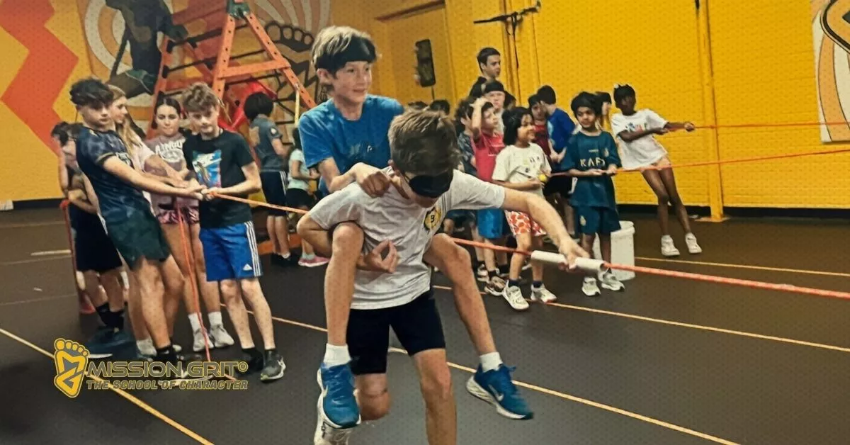 Kids work together during a blindfolded teamwork challenge in Mission Grit’s indoor summer camp program.