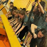 Mission Grit students working together on an indoor obstacle course with ropes and climbing equipment.