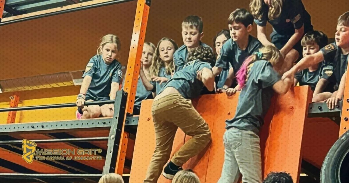 Kids helping each other climb over an obstacle during a Mission Grit team-building event.