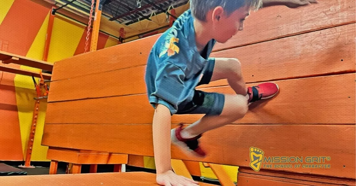 Child climbing over an indoor obstacle during a Mission Grit Xplor session.