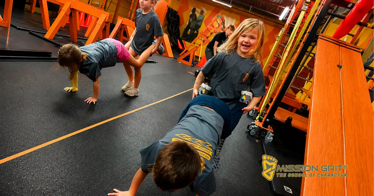 Children completing a partner teamwork challenge during a Mission Grit obstacle course class focused on leadership and cooperation.