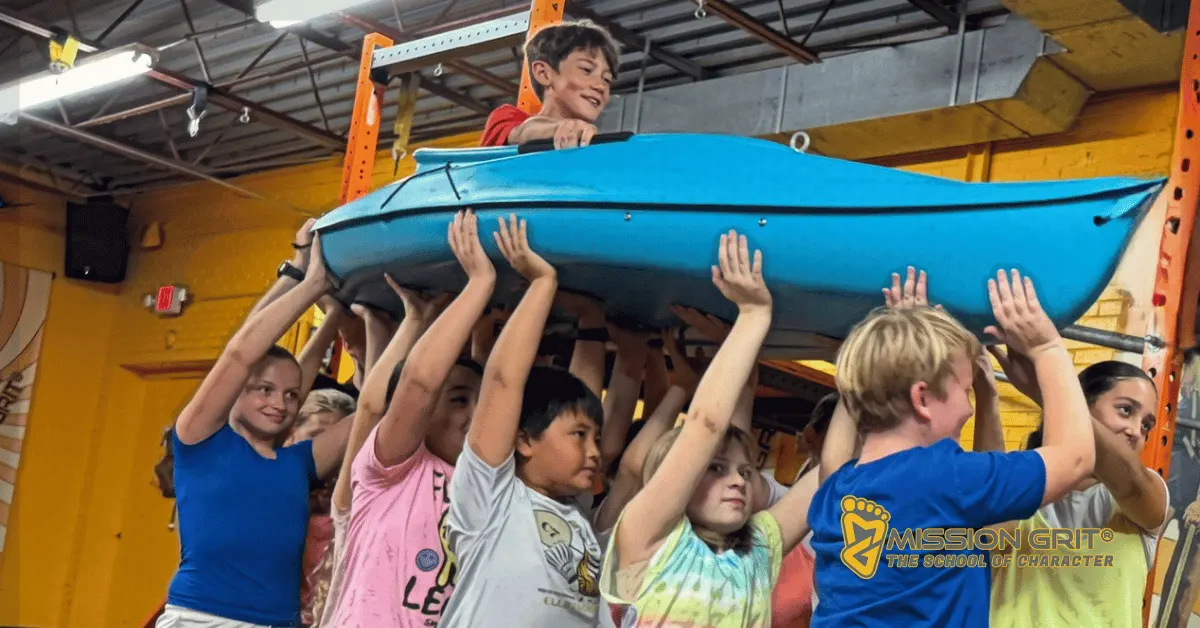 Children working together to carry a kayak during a Mission Grit teamwork challenge that builds leadership and communication skills.