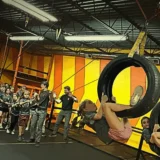 Children climbing hanging tire obstacles while classmates encourage them during a Mission Grit leadership class in Charlotte.