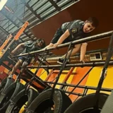 Children climbing across elevated obstacles during a Mission Grit obstacle course class that builds confidence and resilience.