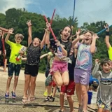 Children celebrating together during an outdoor Mission Grit social skills and leadership activity in Charlotte.
