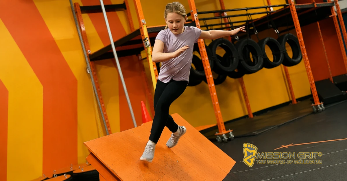 Child balancing on an obstacle during a Mission Grit birthday party activity that builds confidence and coordination.